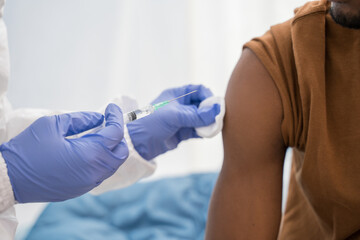 Doctor in medical gloves giving Covid-19 vaccine shot to male patient