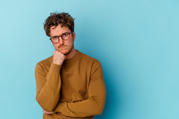 Fototapeta premium Young caucasian man wearing eyeglasses isolated on blue background who feels sad and pensive, looking at copy space.
