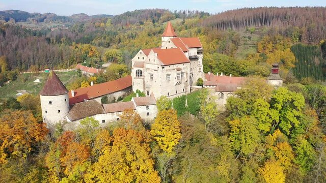 Picturesque autumn landscape with imposing historic Pernstejn Castle on rock above village of Nedvedice, Czech Republic