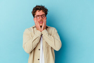 Young caucasian man wearing eyeglasses isolated on blue background whining and crying disconsolately.