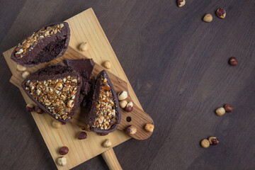 Top view of a cracked stuffed hazelnut and chocolate easter egg on a wooden stand on a wooden table.