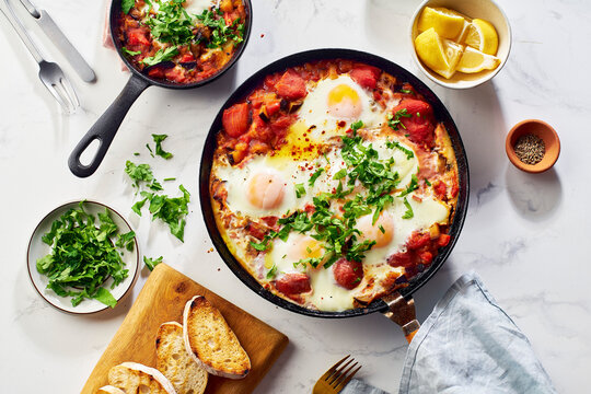 Top view breakfast Shakshuka with vegetables, herbs, tomato sauce and grilled bread slices