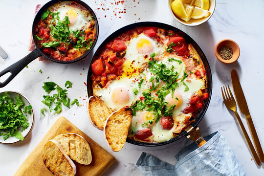 Top view breakfast Shakshuka with vegetables, herbs, tomato sauce and grilled bread slices