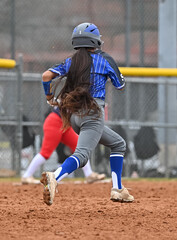 Girl with very long brown hair playing softball in a game