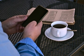 news on a smartphone at a table with a cup of coffee