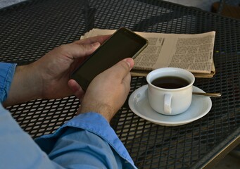 news on a smartphone at a table with a cup of coffee