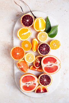 Flat lay citrus fruits with cut up lemons, grapefruits, oranges, blood oranges, and lemons on a cutting board.