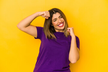 Young indian woman isolated on yellow background raising fist after a victory, winner concept.