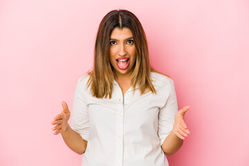 Fototapeta premium Young indian woman isolated on pink background holding something with both hands, product presentation.