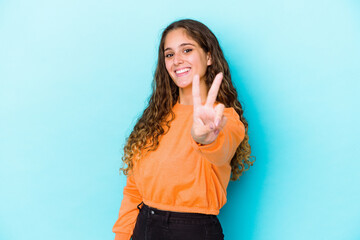 Young caucasian curly hair woman isolated joyful and carefree showing a peace symbol with fingers.