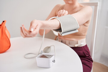 Woman measuring blood pressure herself at home