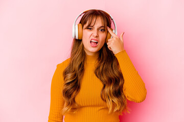 Young caucasian woman listening music with headphones isolated showing a disappointment gesture...