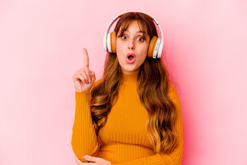 Fototapeta premium Young caucasian woman listening music with headphones isolated having some great idea, concept of creativity.