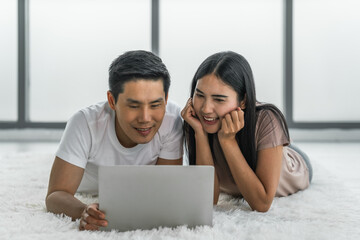 couple lying on floor in living room using laptop working from home