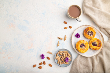 Small cheesecakes with jam and almonds with cup of coffee on a white concrete background. top view, copy space.