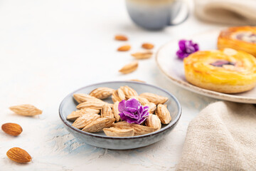 Small cheesecakes with jam and almonds with cup of coffee on a white concrete background. Side view, selective focus.