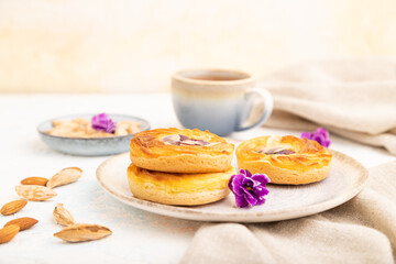 Small cheesecakes with jam and almonds with cup of coffee on a white concrete background. Side view, selective focus.