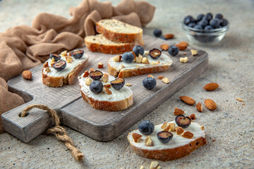 Fototapeta na wymiar Bruschetta with creamy ricotta almonds and blueberries. A healthy, nutritious snack.