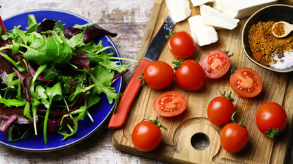Cherry tomatoes, mix salad, spices, white cheese. Ingredients for making a healthy salad. Healthy food concept.