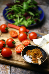 Cherry tomatoes, mix salad, spices, white cheese. Ingredients for making a healthy salad. Healthy food concept.