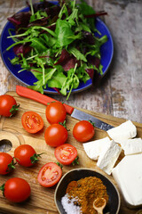 Cherry tomatoes, mix salad, spices, white cheese. Ingredients for making a healthy salad. Healthy food concept.