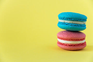 blue macaroon cake with white cream lies on a pink macaroon cake with white cream on a yellow background on the right horizontal photo