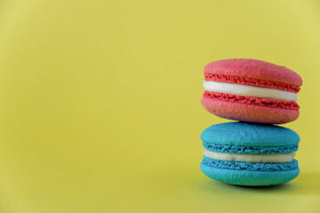 pink macaroon cake with white cream lies on a blue macaroon cake with white cream on a yellow background on the right horizontal photo