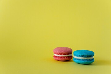 pink and blue macaroon cakes with white cream on a yellow background on the right horizontal photo