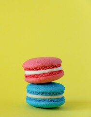 pink macaroon cake with white cream lies on a blue macaroon cake with white cream on a yellow background in the center vertical photo