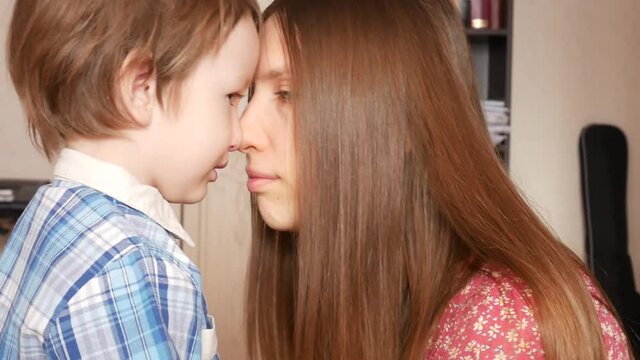 A young lovely woman consoles her little son bringing her face closer to his face and whispering something close-up