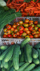 Assorted vegetables in the basket. There are cucumbers, tomatoes, long beans