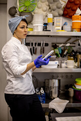 Confident woman confectioner in uniform chatting use smartphone at catering kitchen