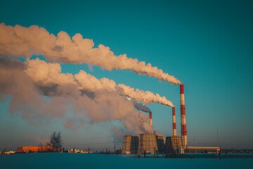 smoke from a working thermal power plant covers the blue sky in a frosty early morning