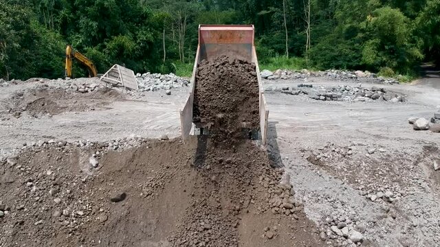 Dump truck unloads sand and rock in processing site of open pit mine in Magelang