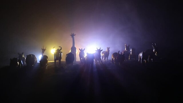 A group of animals are grouped together at foggy night with burning colorful background. Animals Running Escaping to Save Their Lives from fire. Selective focus.