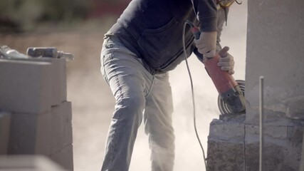 Construction worker cuts concrete with angle grinder, slow mo