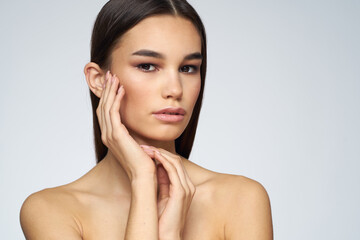 Woman with long hair bared shoulders clean skin body care light background