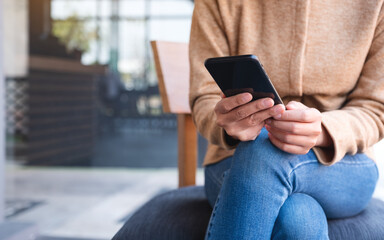 Closeup image of a woman holding and using mobile phone