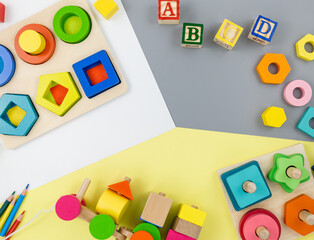 Wooden toys, blocks, a train on yellow gray background. Trendy cute baby first toys. Eco-friendly, plastic-free set of accessories for kids. Toys for kindergarten, preschool or daycare. Close up	