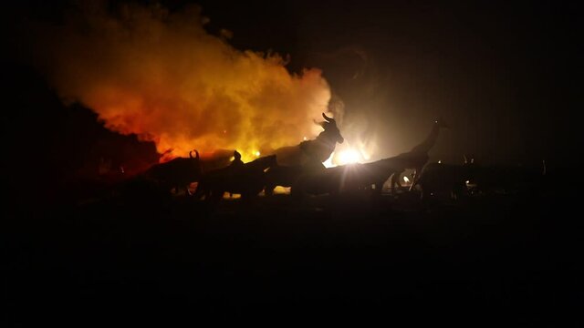 A group of animals are grouped together at foggy night with burning colorful background. Animals Running Escaping to Save Their Lives from fire. Selective focus.