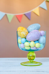 Easter sweet candies cute flags and pastel colored eggs in a beautiful glass vase. Easter celebration concept.