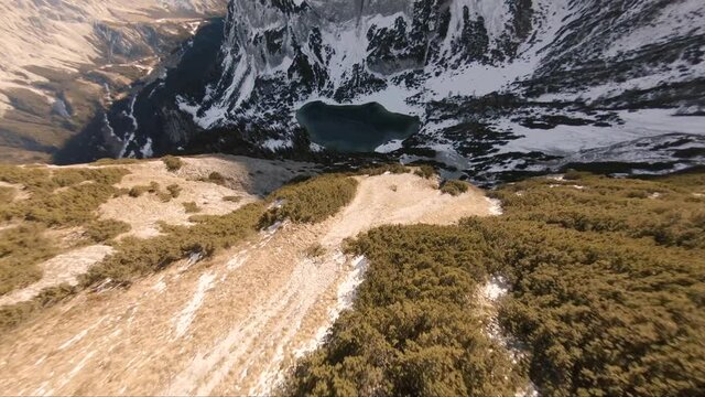 Cinematic aerial landscape view over Seebensee lake surrounded by snow capped mountains, in a valley 