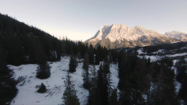 Aerial landscape view over an austrian snow capped mountain forest, in a valley in wintertime