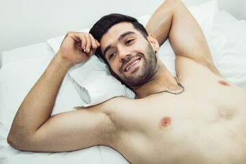 Fototapeta na wymiar Handsome shirtless man laying on bed and have positive thinking with looking away. Seductive attitude and nice attitude sexy concept