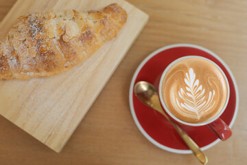Top view Close up hot cappuccino, latte on table with blur coffee shop background. Hot cappuccino coffee on wood table with blur croissant background. breakfast at coffee shop soft focus select coffee