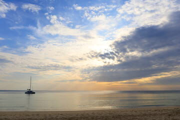Landscape of bright sea and clouds with the golden rays of the sun come out from behind the clouds with silhouette of ship boat stay on sea.