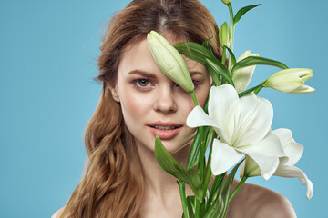 Woman with a bouquet of white flowers on a blue background naked shoulders beautiful face