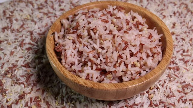 Cooked and raw mixed low glycaemic index healthy rice grain basmati millet buckwheat red rice in wooden bowl spoon bed of rice