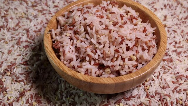Cooked and raw mixed low glycaemic index healthy rice grain basmati millet buckwheat red rice in wooden bowl spoon bed of rice