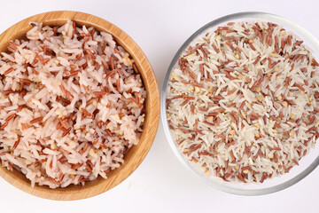 Cooked and raw mixed low glycaemic index healthy rice grain basmati millet buckwheat red rice in wooden and glass bowl on white background